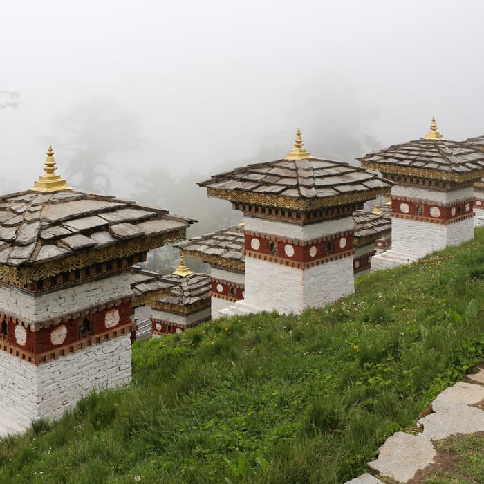 A row of white chortens and prayer flags at Dochula Pass in Bhutan